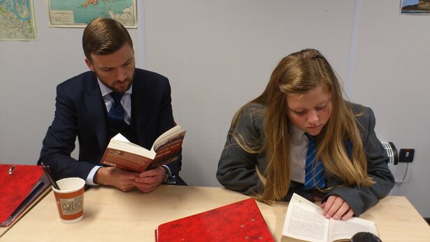 Picture of Mr Faith reading alongside a student